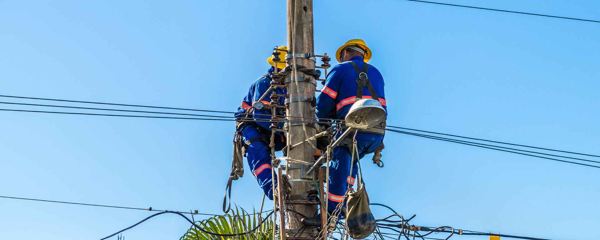 Electricians working on power lines atop a utility pole.